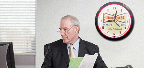 Business man working while a neon clock glows steadily in the background